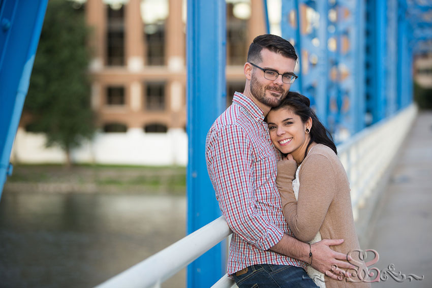 02-engaged-couple-embrace-on-blue-bridge-grand-rapids-photographer