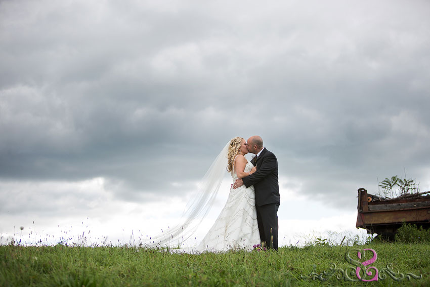 31-bride-and-groom-kiss-on-hill-with-dramatic-sky-lawrence-wedding-photographer