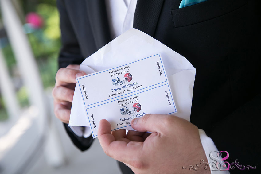 16-groom-holds-gift-football-tickets-lawrence-wedding-photographer
