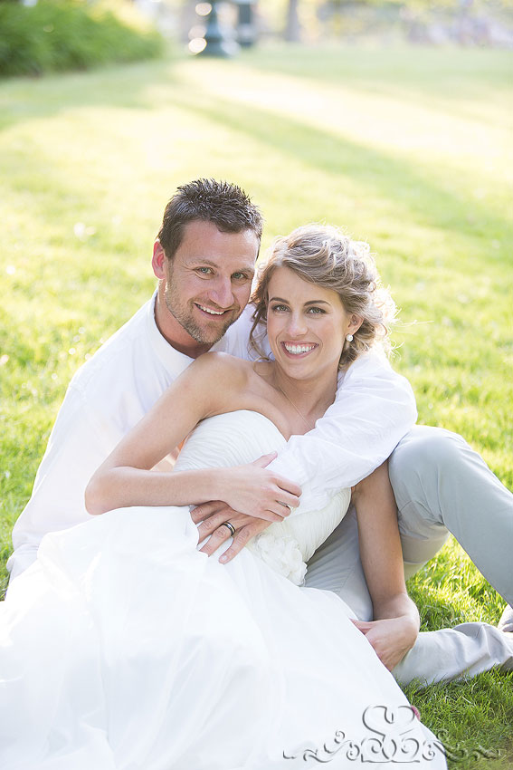 51-bride and groom sit on grassy hill smiling holland michigan photographer