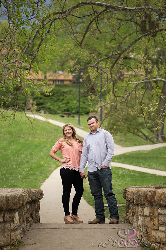 08-man and woman smile and hold hands on bridge lawrence wedding photographer kansas university campus engagement session